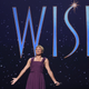 Ariana DeBose stands in front of a title treatment for Wish.